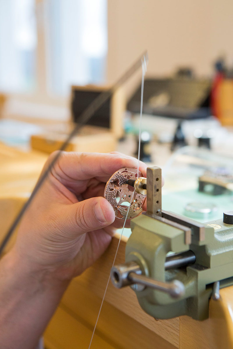 Picture of an Alchemists watchmaker working on the Cu29 movement's bottom plate